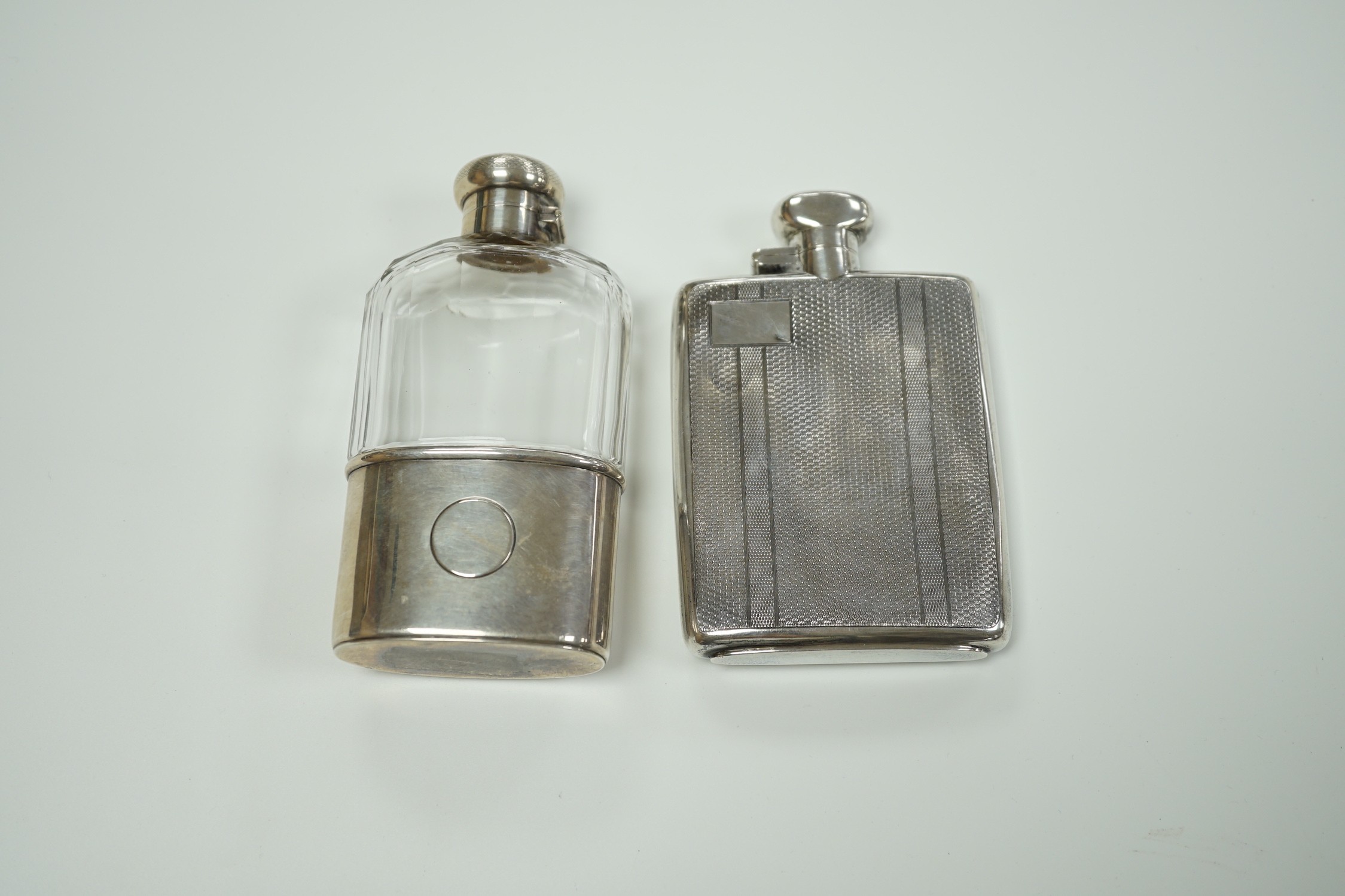 A George V engine turned silver hip flask, by Robert Pringle & Sons, Chester, 1929, 12.8cm and an earlier silver mounted glass hip flask, London, 1910.